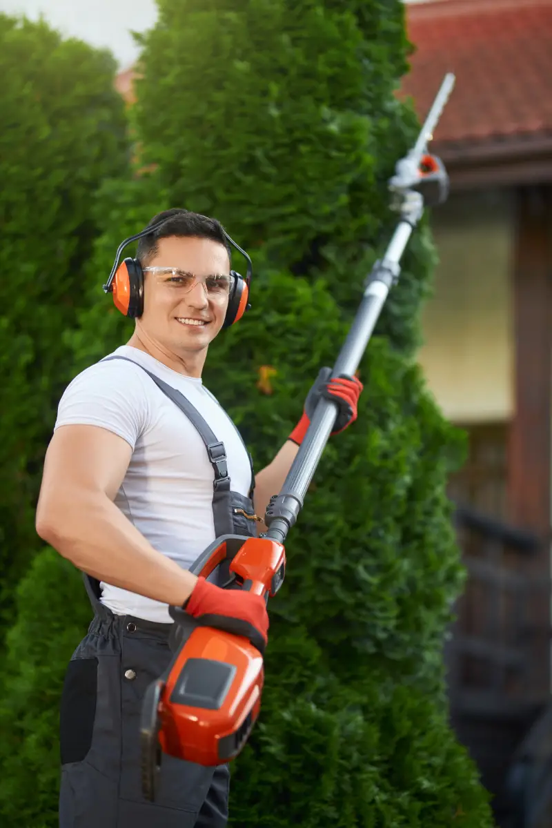 smiling-gardener-holding-petrol-hedge-cutter-outdoors smiling-gardener-holding-petrol-hedge-cutter-outdoors